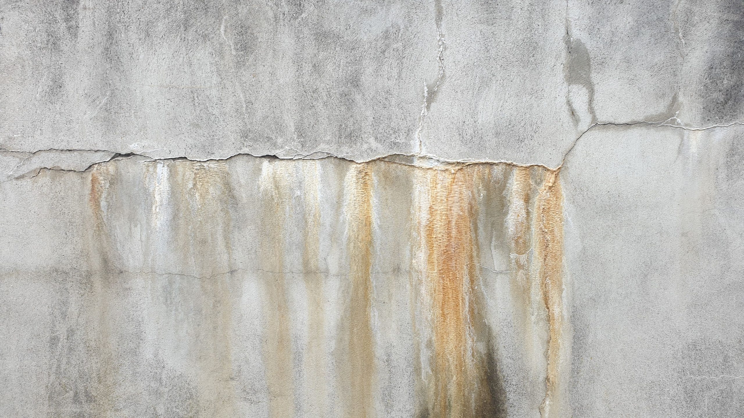 Mur en beton endommage avec fissures et taches de salpetre